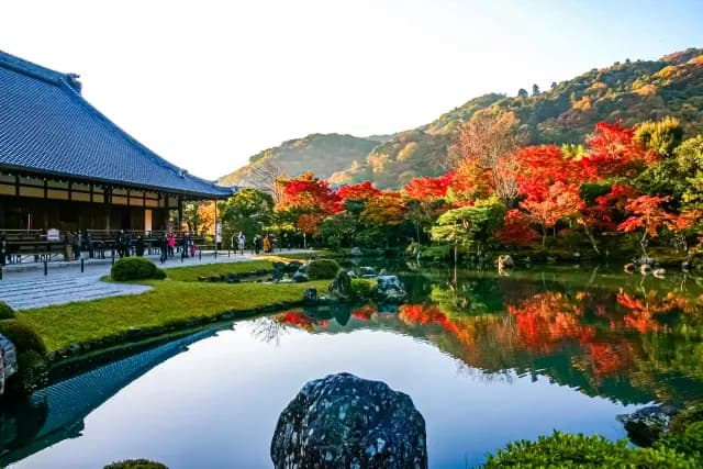 紅葉の山を映す寺の池泉庭園