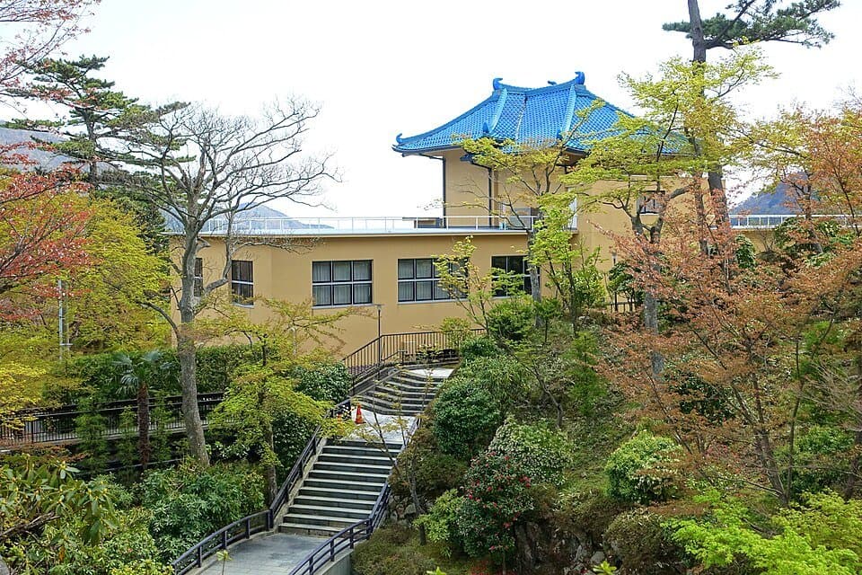 青い屋根の建物と、新緑の木々のあいだを上る石段