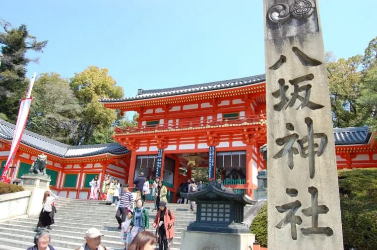 朱塗りの門と「八坂神社」の石柱