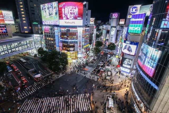 Crowds crossing the Shibuya Scramble Crossing at dusk, with Center Gai signage in view