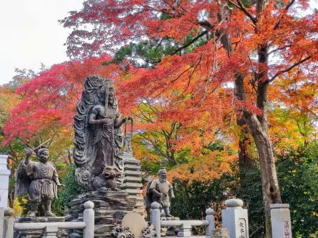 A stone statue beneath autumn maples