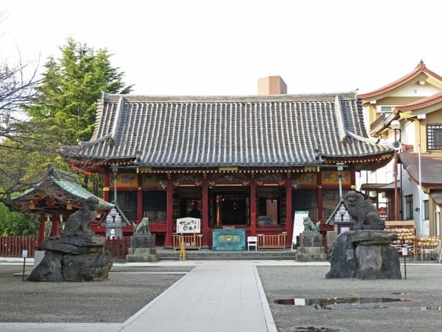 赤い社殿と、参道の両脇の岩に乗った狛犬
