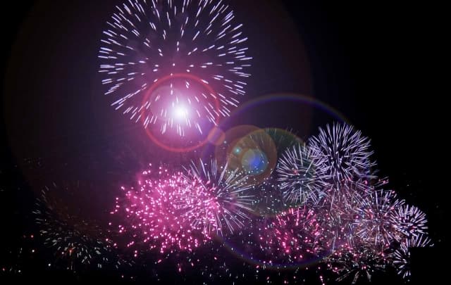 Fireworks bursting in the night sky at the Itabashi Fireworks Festival, with layered pink and white blooms scattering points of light against the darkness.