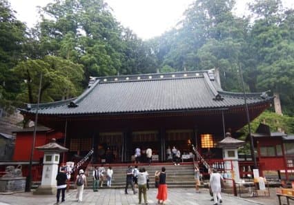 高い木々に囲まれた社殿と参拝客